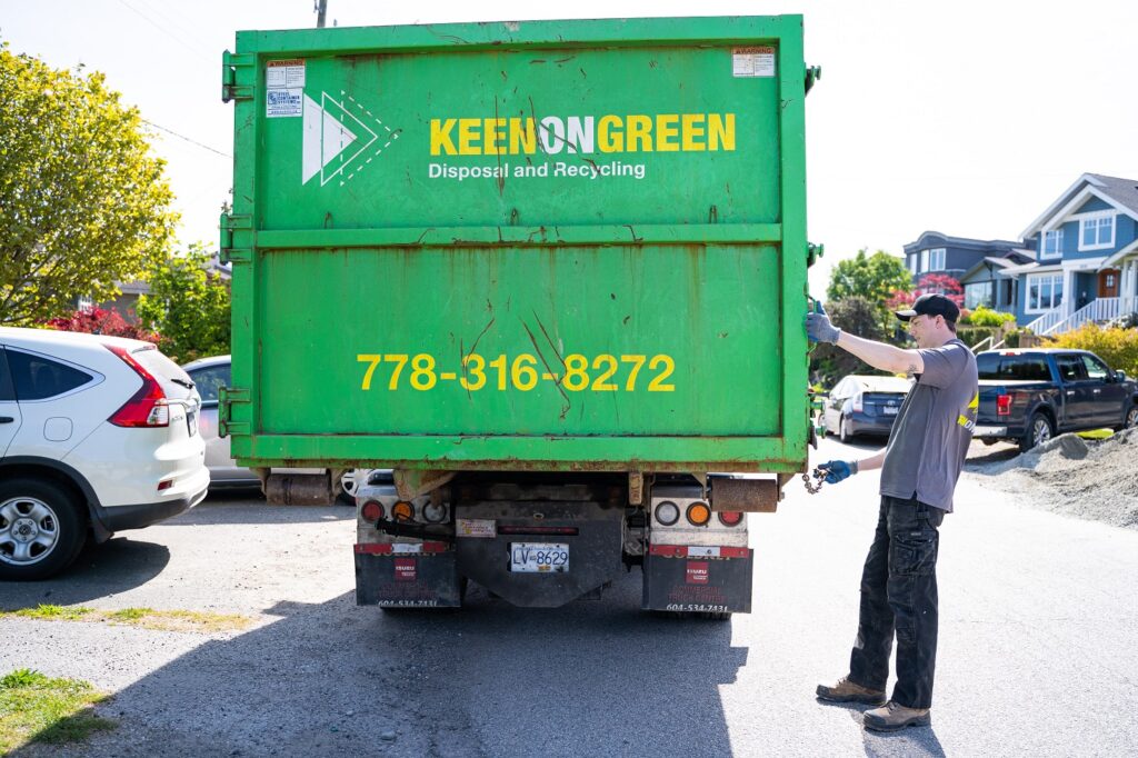 Professional junk removal services in Vancouver BC - a man standing next to a green garbage truck